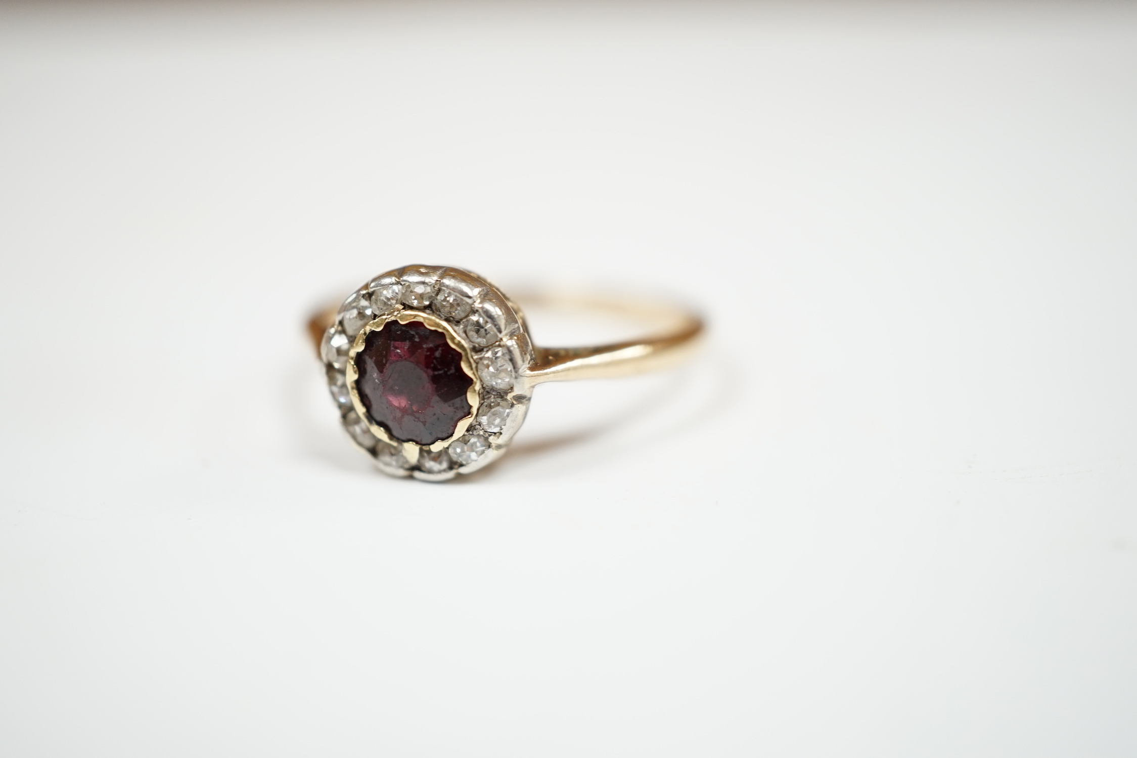 A 9ct, garnet and diamond set circular cluster ring, size R, gross weight 2.8 grams. Condition - poor